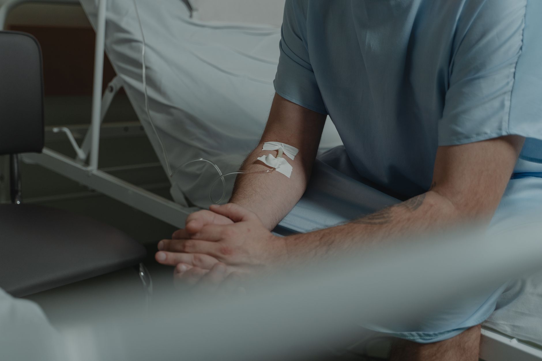 Patient resting in a hospital bed while a nurse prepares them before a cardiac procedure