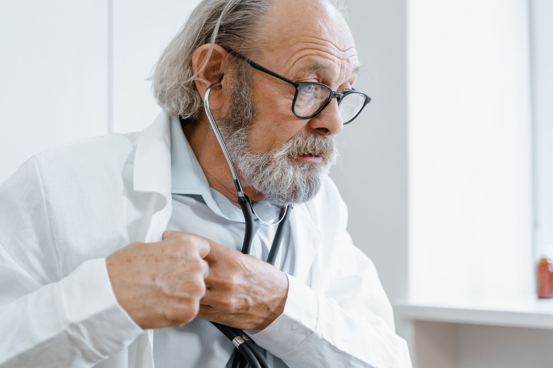 A doctor listening to an elderly patient's heart with a stethoscope during a cardiac check-up