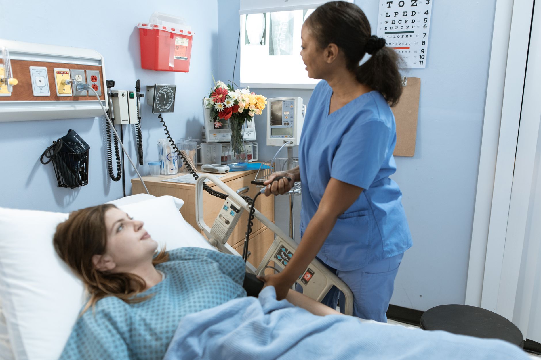 A patient resting and recovering in a hospital bed with a nurse nearby