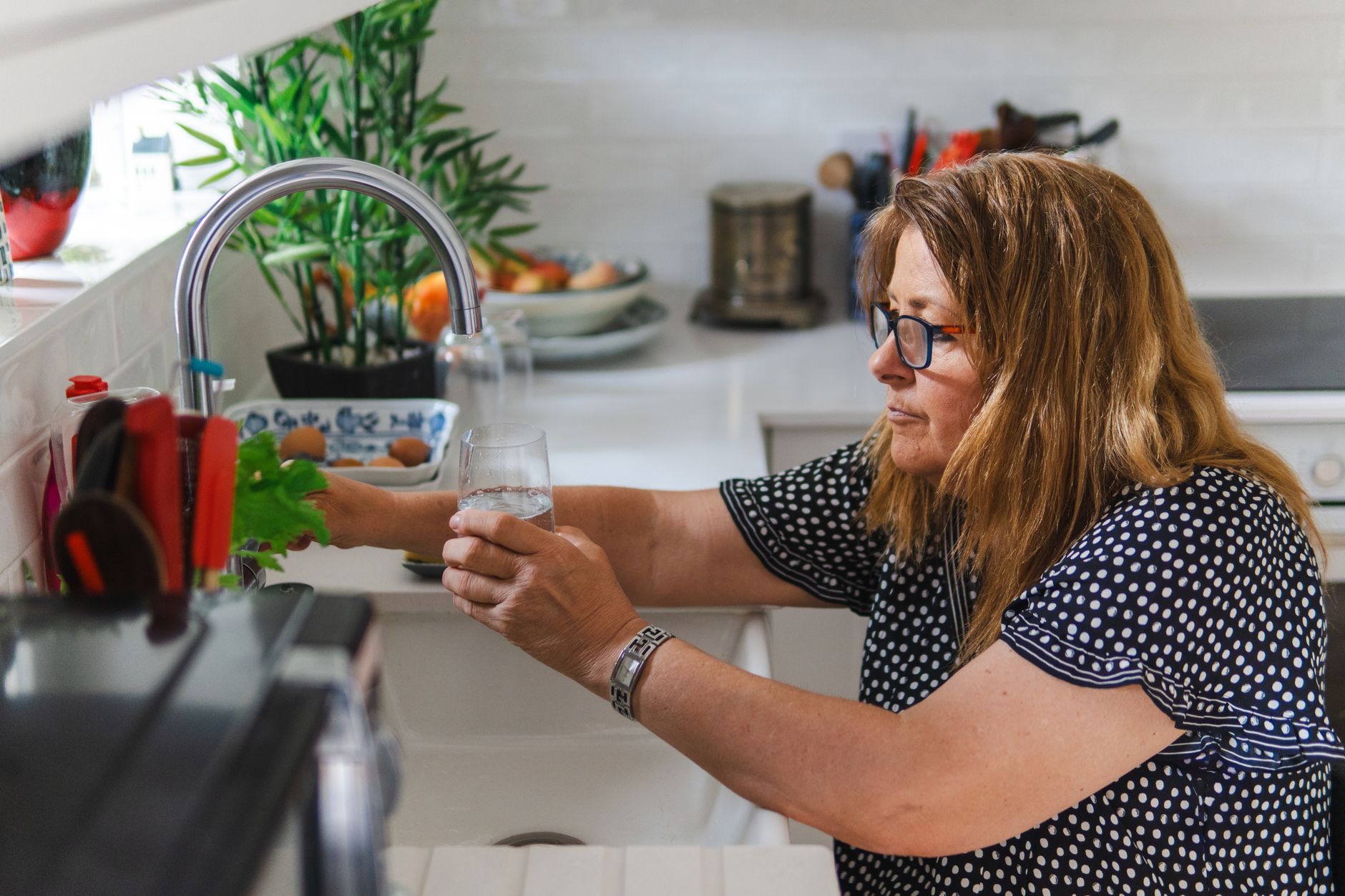 A person staying well-hydrated by drinking a glass of water, important for heart patients