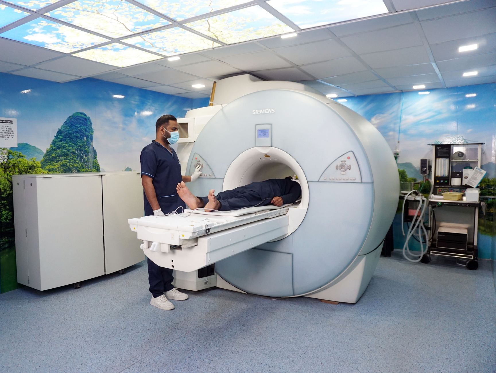 A patient lying comfortably in a CT scanner while a nurse prepares them for the scan