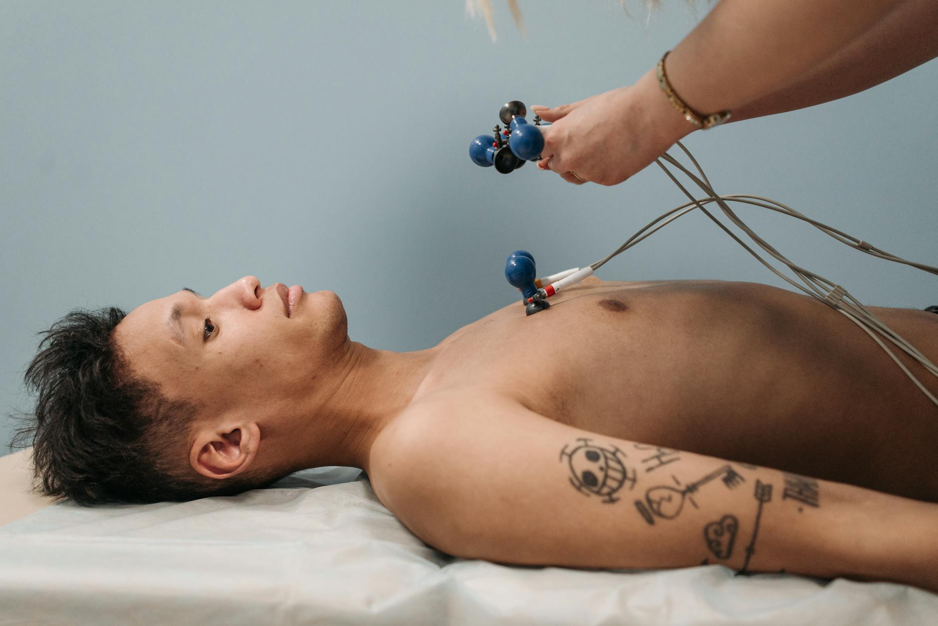 A doctor attaching ECG electrode patches to a patient's chest for a heart tracing test