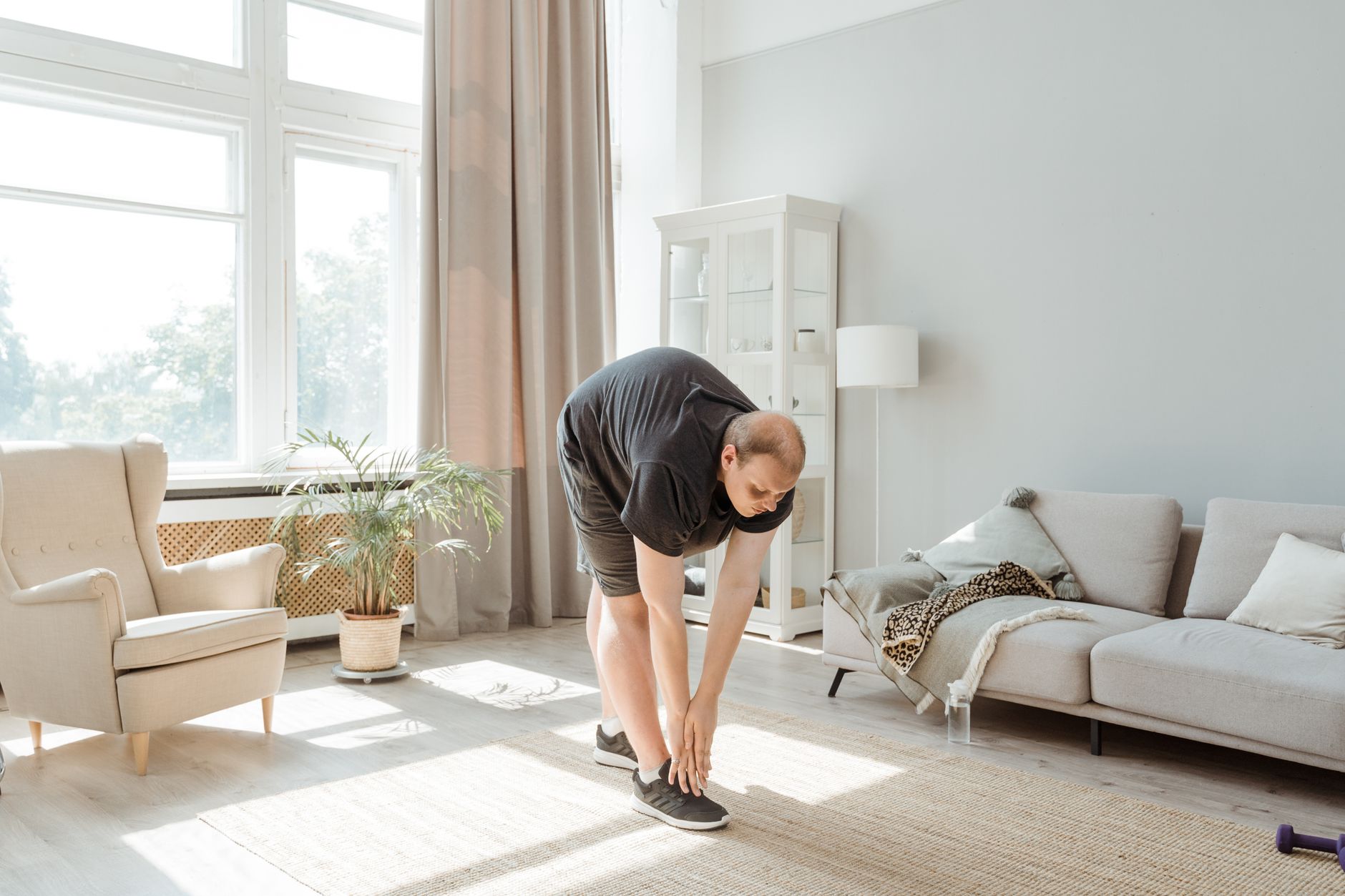 A person performing gentle stretching exercises at home during cardiac recovery