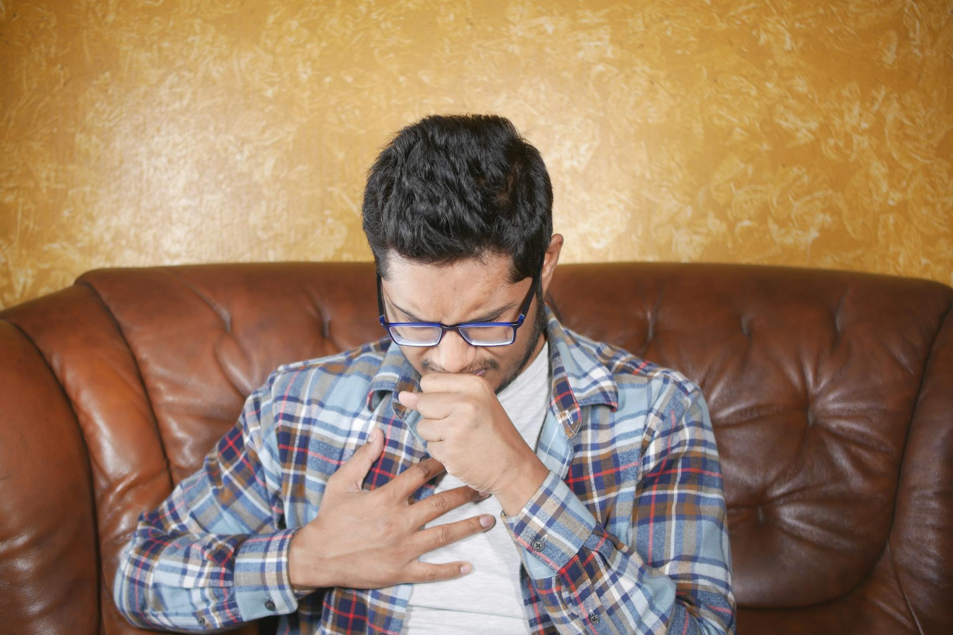 A person experiencing chest discomfort while seated, illustrating a common heart attack warning sign