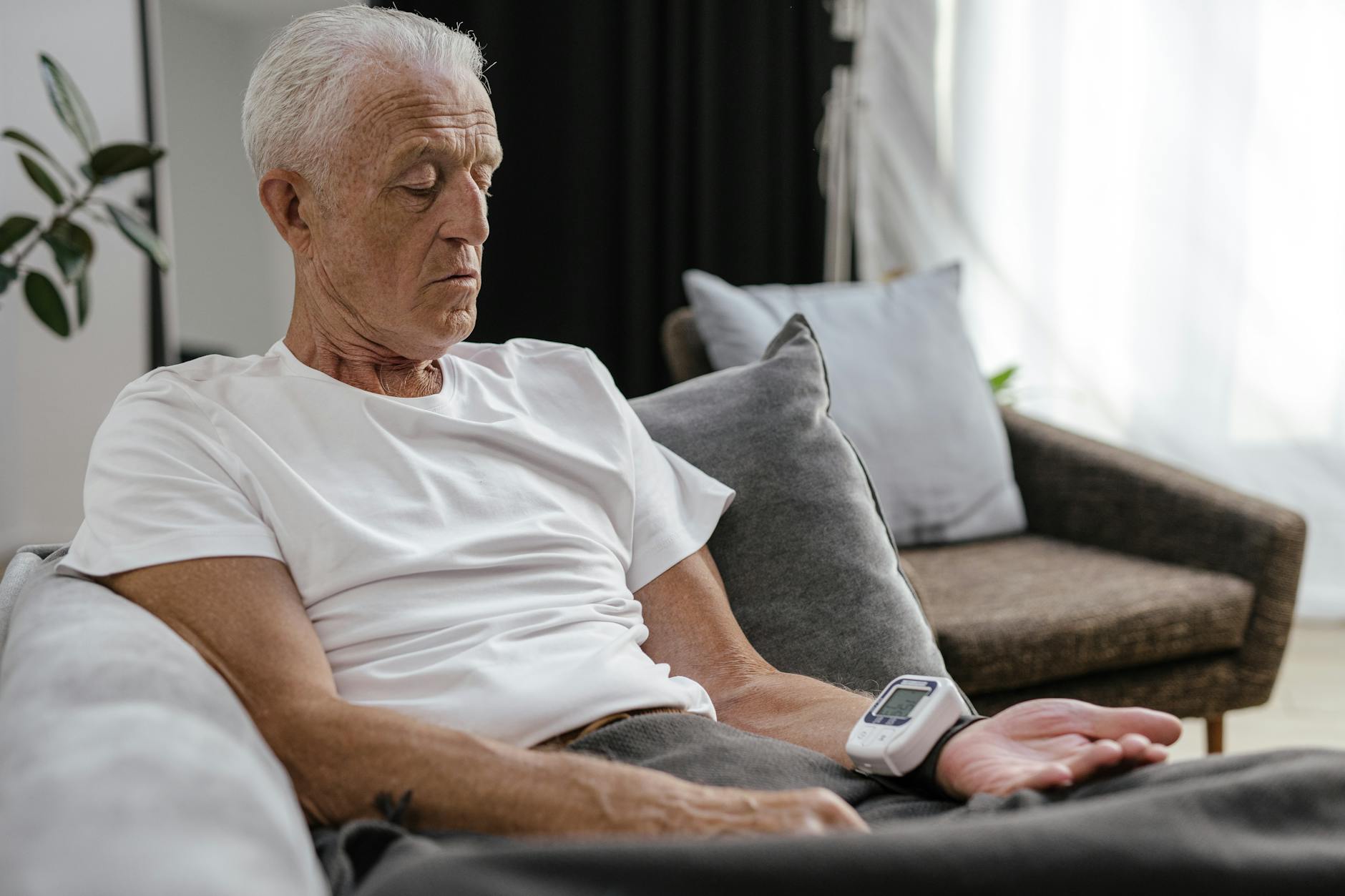 An older man checking his blood pressure at home to monitor heart health