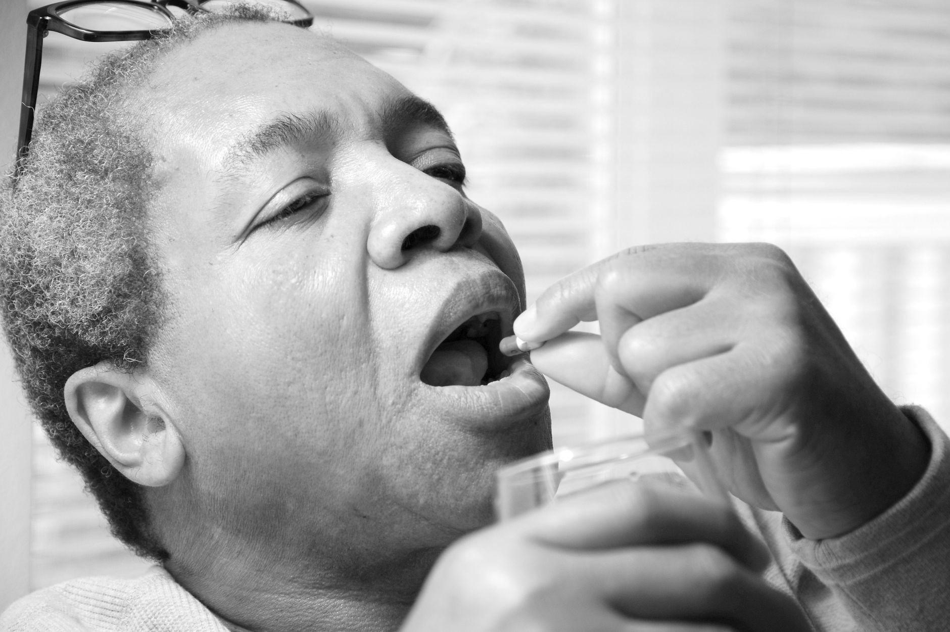 A person taking prescribed daily medication with a glass of water