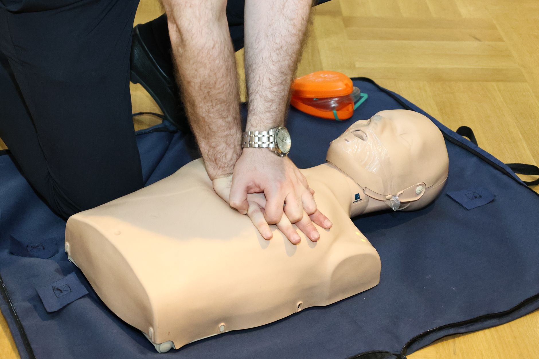 A person practising CPR chest compressions on a training mannequin during a first-aid class