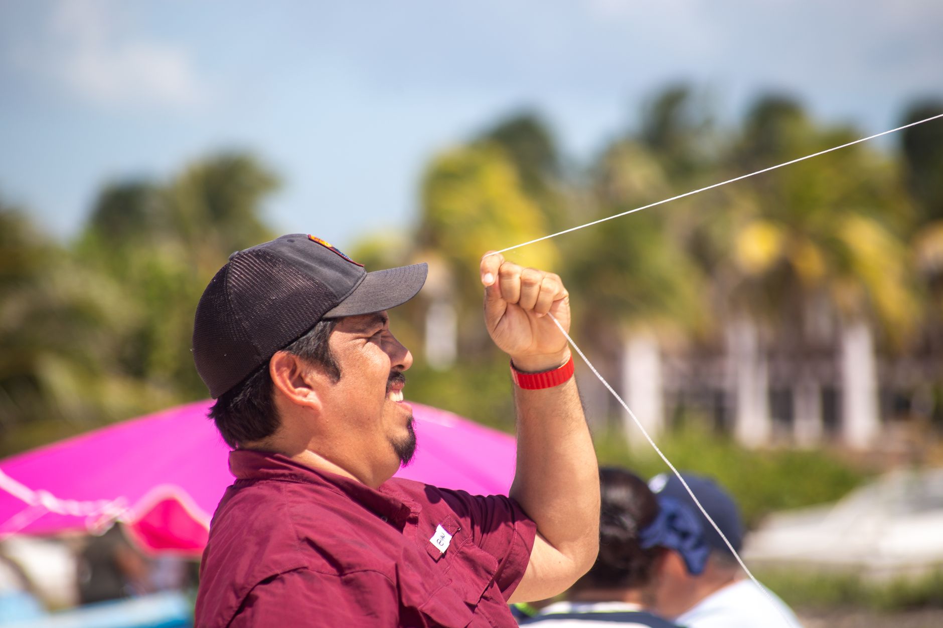 A man flying a kite on a rooftop on a sunny day, arms extended with kite string