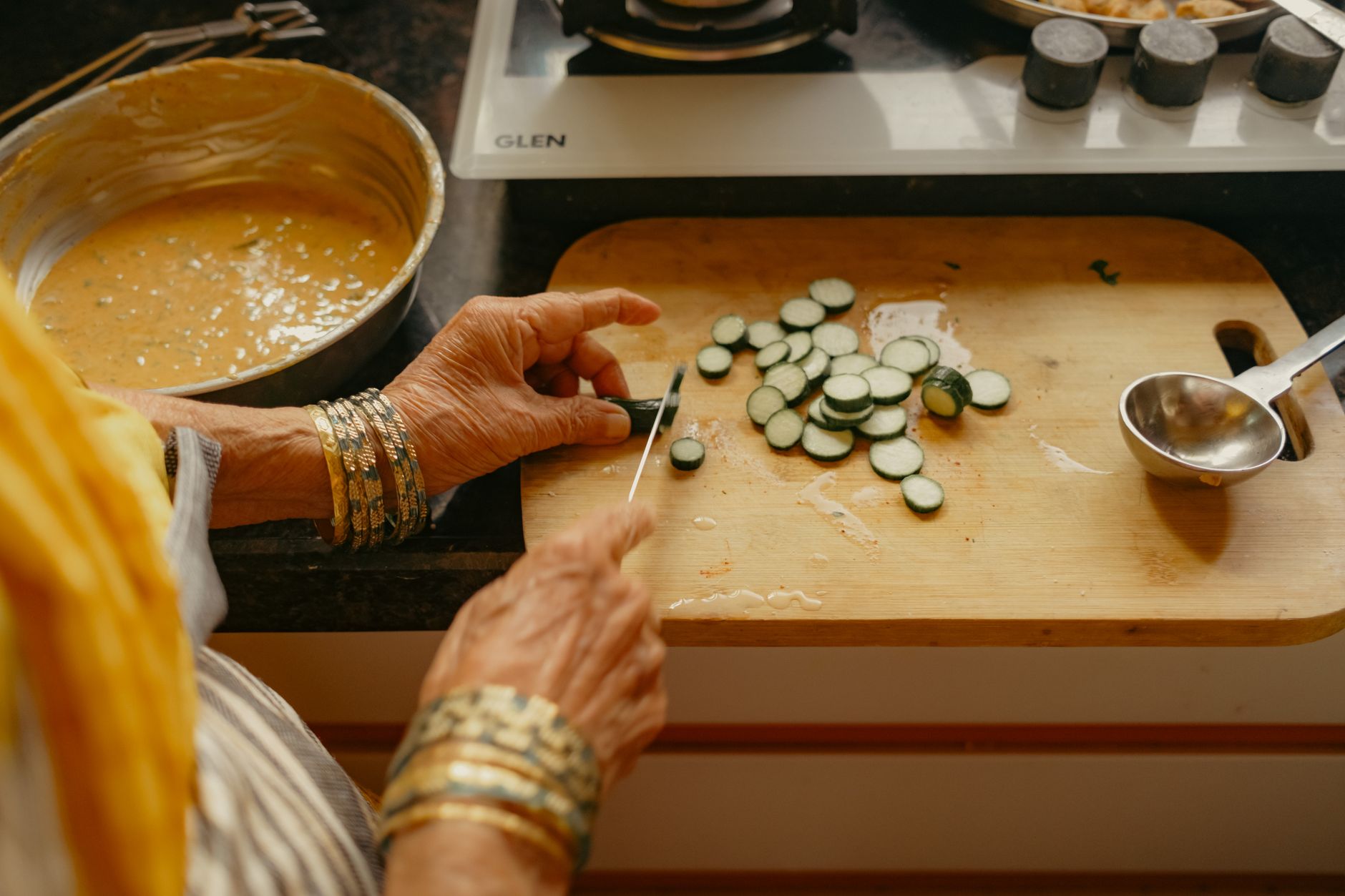 A woman preparing fresh vegetables in a bright Indian kitchen