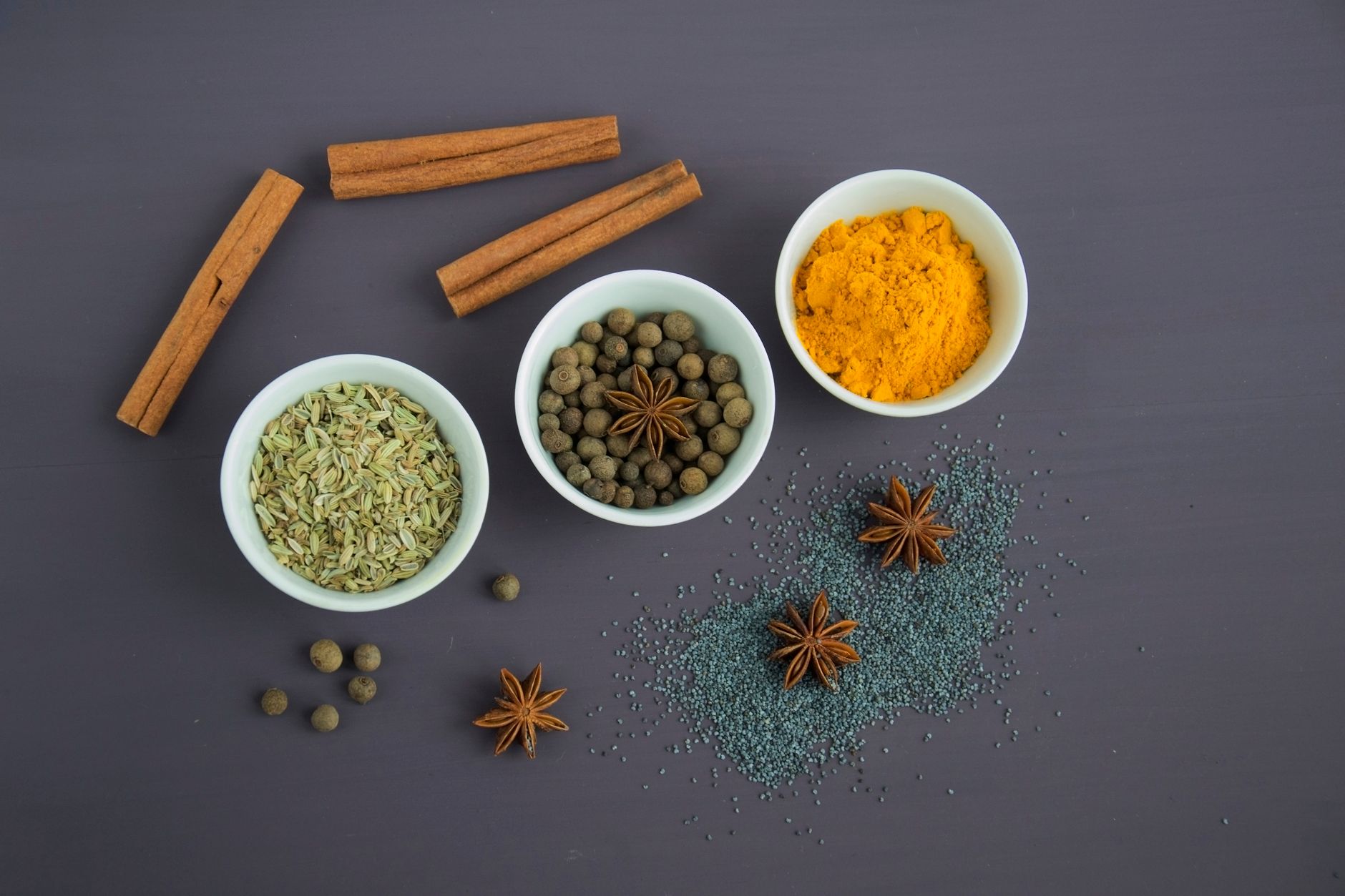 Assorted aromatic spices, seeds, and dried herbs arranged in small bowls