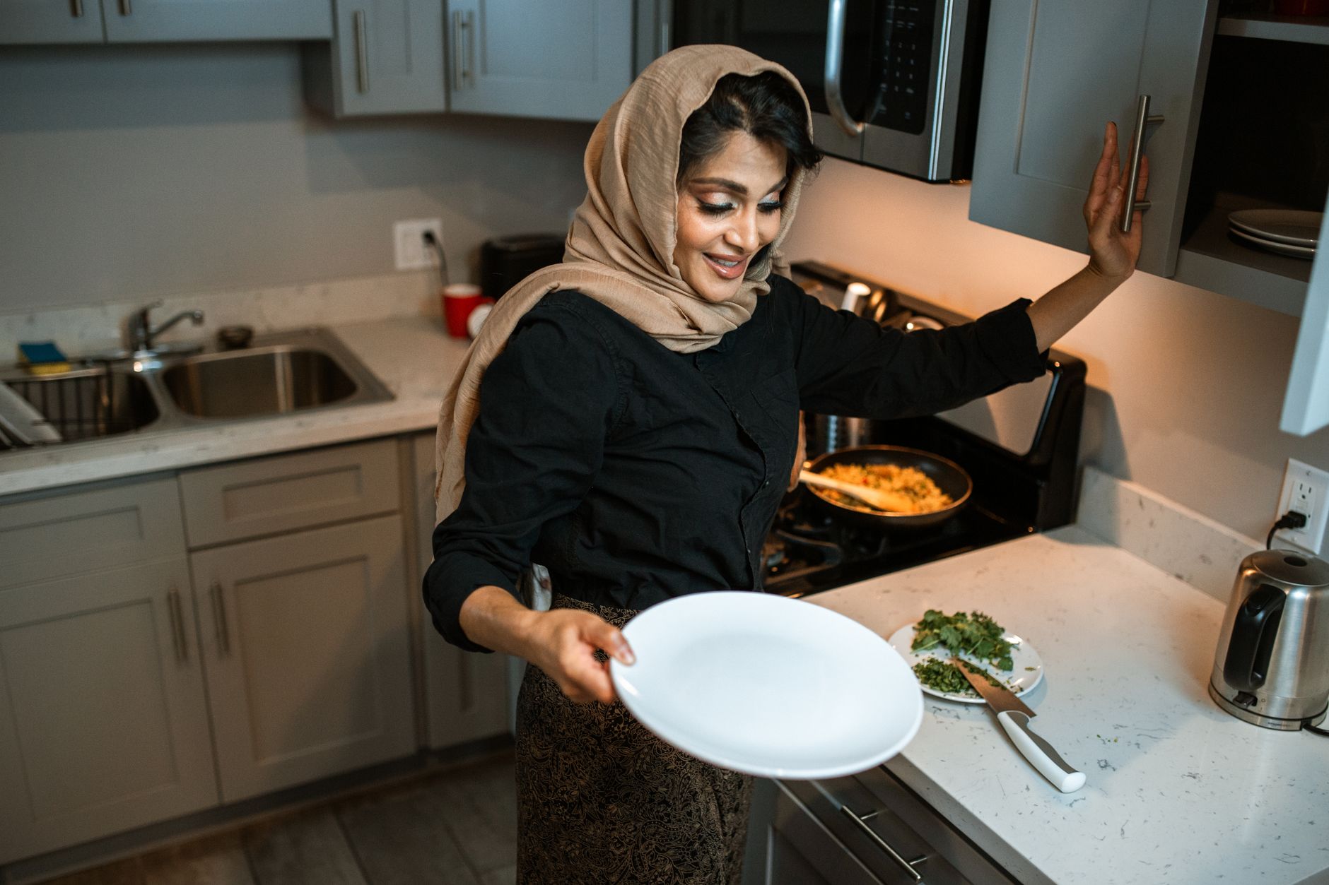 Woman preparing a low-oil meal on a stovetop in an Indian kitchen