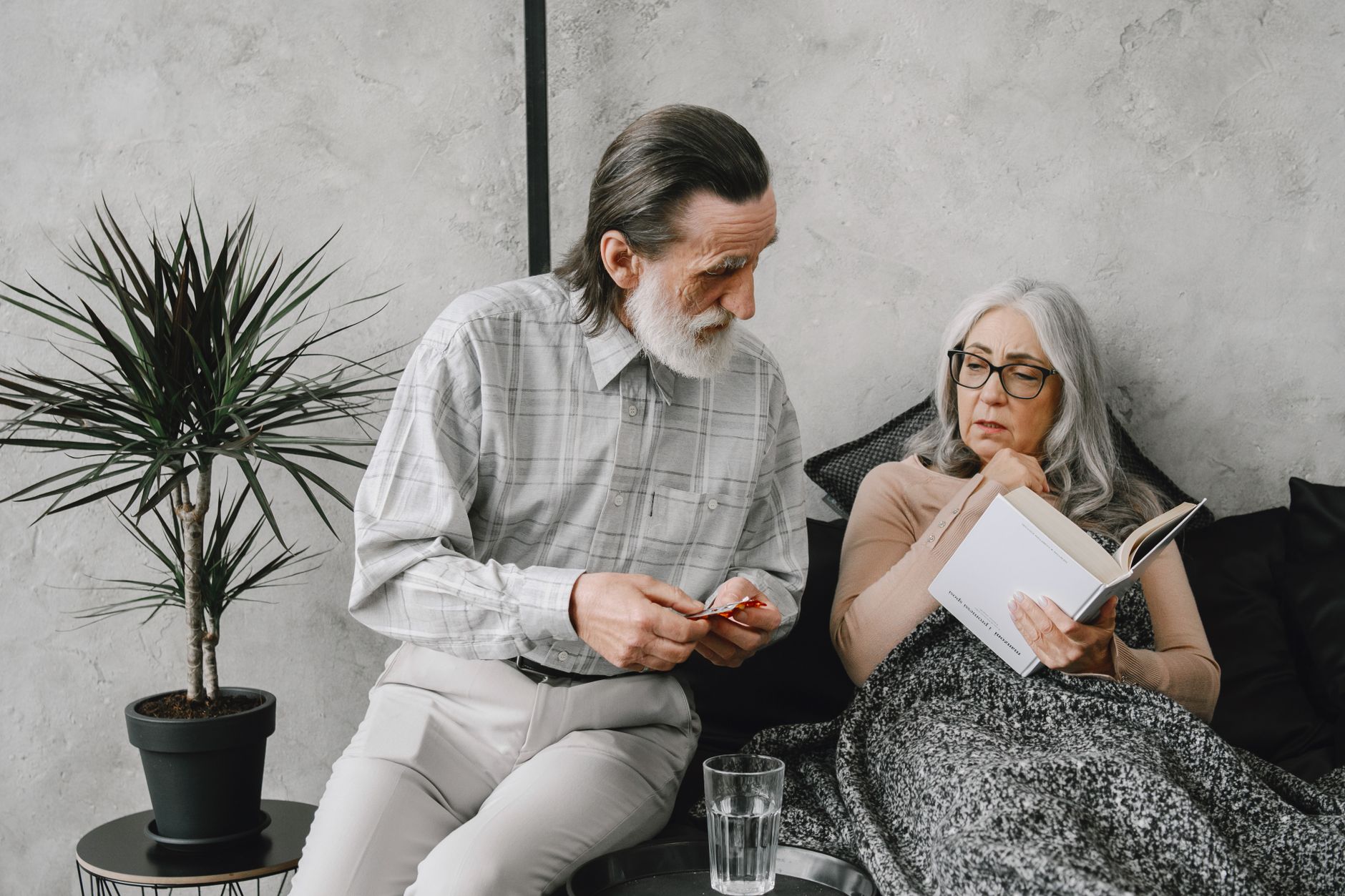 An older couple carefully reviewing medicine packaging at home before taking it