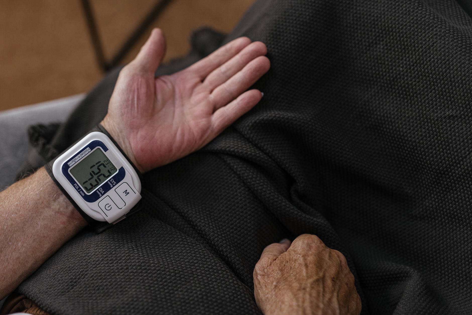 An older adult monitoring their blood pressure at home using a digital device