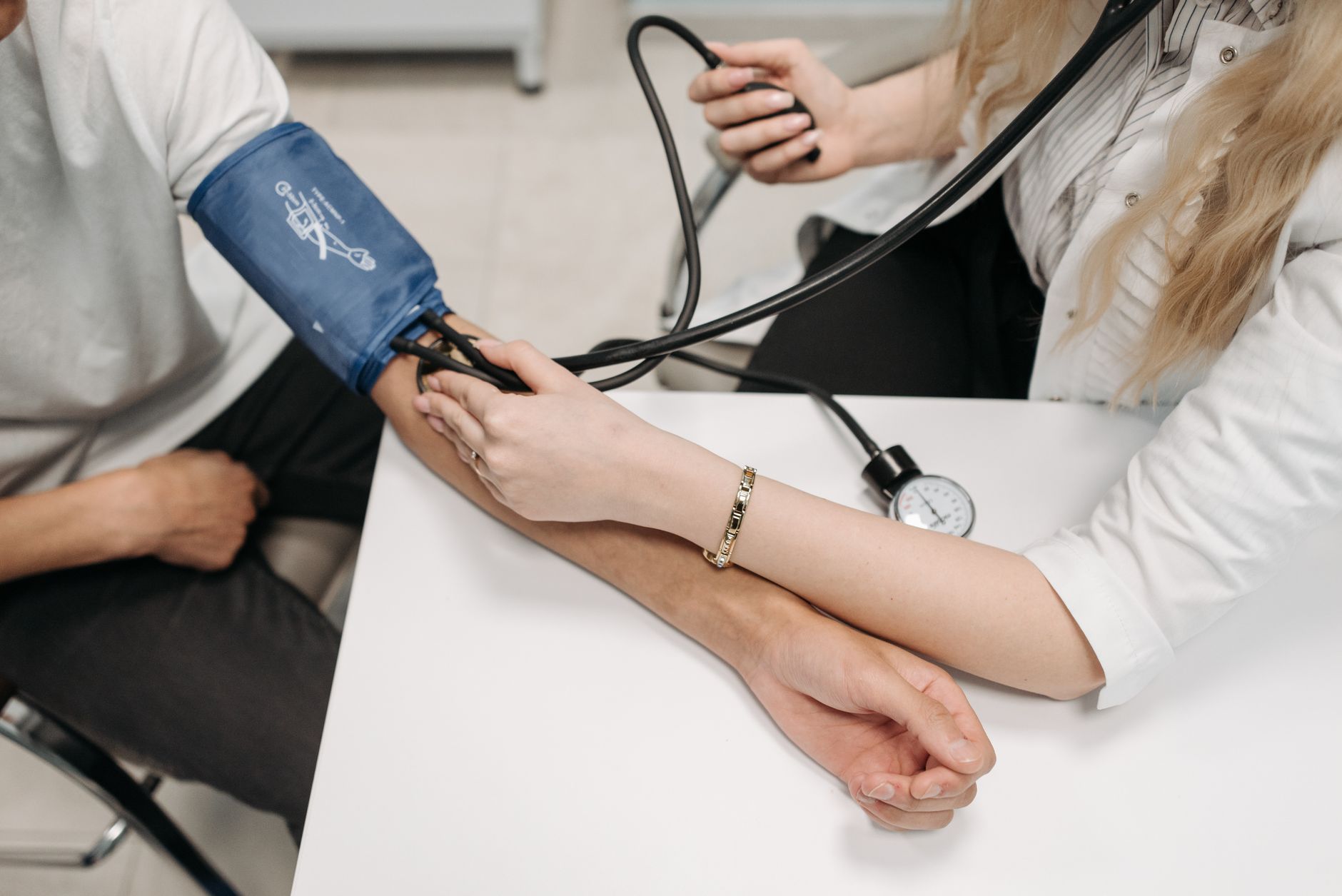A doctor checking a patient's blood pressure — routine monitoring is key for desk workers