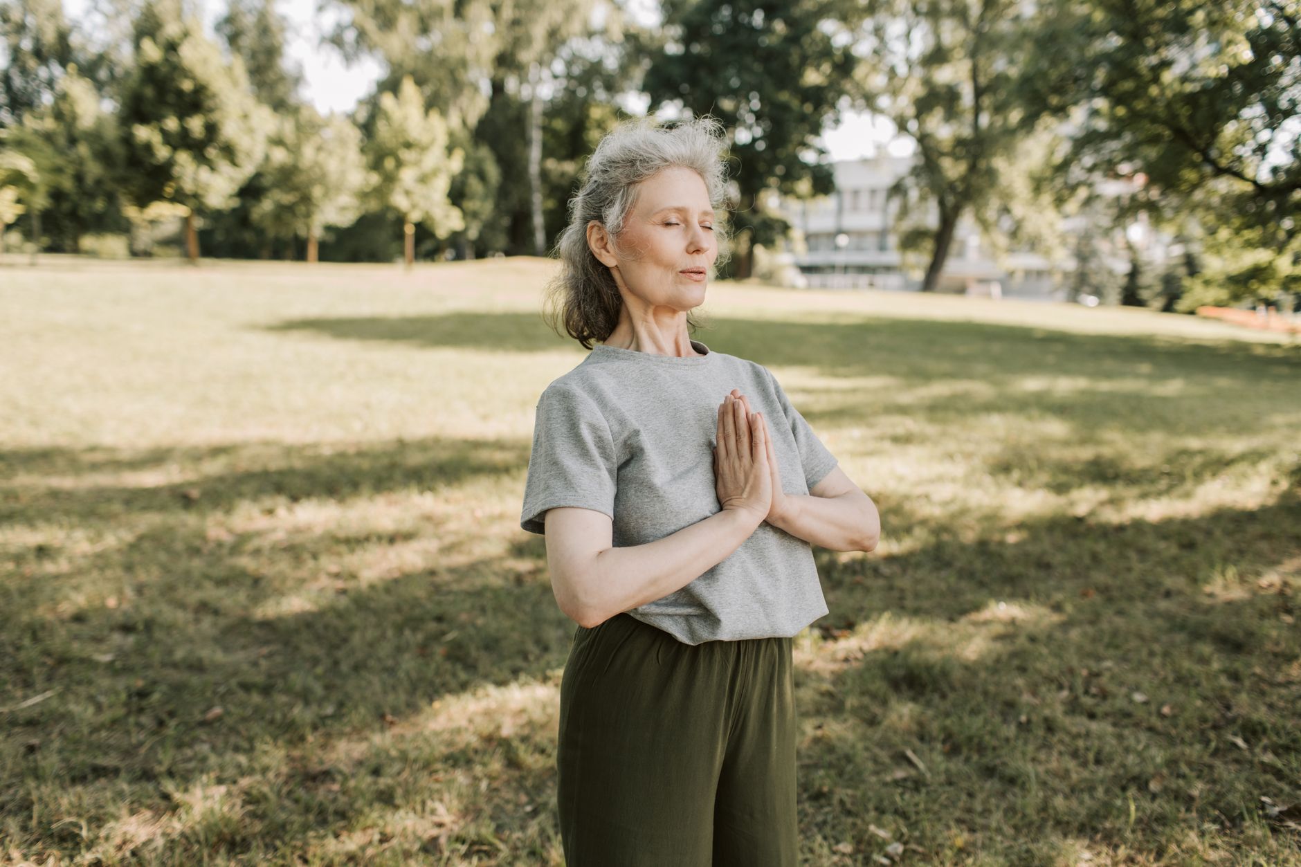 A senior person meditating outdoors to manage stress and anxiety